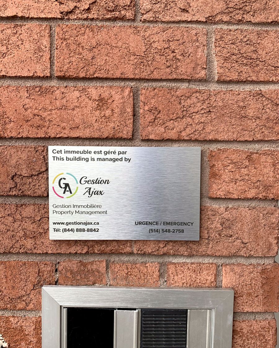 Plaque Gestion Ajax sur une façade en brique